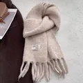 Detailed texture of thick knit apricot scarf with tassels on casual winter outfit - Off White