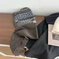 Detail view of Fair Isle knit balaclava scarf with blue and white pattern on wood background - Camel
