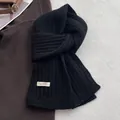 Dettaglio della sciarpa in pura lana nera che mostra la maglia spessa e l'etichetta del materiale - Nero