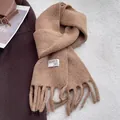 Dettaglio ravvicinato di una sciarpa in lana color cammello con nappe e etichetta tessuta - Cachi