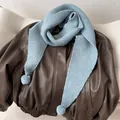Detail of light blue knit triangle scarf with soft pom-poms on a leather jacket - Fog Blue