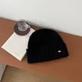 Close-up of black 100% Australian wool knit hat with stylish silver metal brand plate - Black