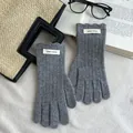 Nahaufnahme grauer Wollstrickhandschuhe mit Rippmuster und Wellensaum am Bündchen - Grau
