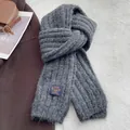 Dettaglio di una sciarpa in maglia grigio scuro con trama a coste ed etichetta - grigio scuro