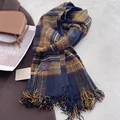 Gros plan détaillé d'une écharpe à carreaux bleu et marron avec franges et étiquette tissée - Noir