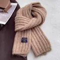 Primo piano di sciarpa in maglia spessa caramello con trama a coste e toppa vintage - Cammello