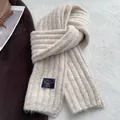 Detail shot of chunky knit scarf texture in beige with vintage brand label on top - Cream Rice