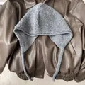 Close-up of grey wool knit balaclava with earflaps on a vintage leather jacket background - Gray