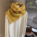 Detailed close-up of ginger yellow chunky knit hooded scarf with brand label detail - Lemon Yellow