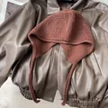 Flat lay of a brown faux leather jacket and brick red knit balaclava with warm wool texture - Coffee