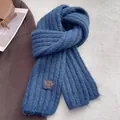 Detailed close-up of blue chunky knit scarf with texture and decorative fabric label - Blue