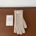 Detail of beige wool knit glove featuring vertical ribs and an ERET WOOL fabric label - Off White