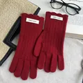 Detailansicht dunkelrote Wollstrickhandschuhe mit Wellensaum und Markenetikett - Rot