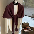 Detalle de chal de lana granate con pompón combinado con un jersey blanco suave - Vino Tinto y Gris