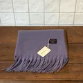 Detalle de bufanda violeta de cachemira sintética con flecos y etiqueta sobre madera - Morado