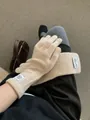 Detail of cream knitted gloves with vintage label on wrist for winter warmth - Apricot