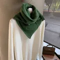 Detail of green knit triangular scarf paired with white sweater and stylish accessories - Vintage Green