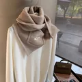 Detailed close-up of thick beige chunky knit scarf with premium brand woven label - Oatmeal Beige