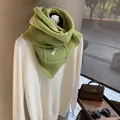 Close-up of green wool knit scarf texture with brand label on a white cashmere sweater - Light Green