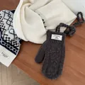 Détail de moufles en tricot gris foncé et écharpe crème à motifs géométriques sur bois - Gris Premium