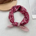 Dettaglio di un foulard bordeaux con motivo paisley annodato su pelliccia bianca - Bordo Rosa