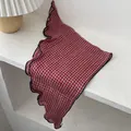Close-up of red and white plaid scarf with navy blue ruffled edges on a white table - Small Plaid Red