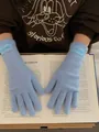 Detail of light blue knitted gloves with woven label on a book for warm winter style - Azure Blue