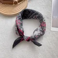 Detailed view of paisley silk scarf knotted elegantly on a wooden tray with a leather strap - Black