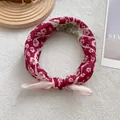 Gros plan détaillé d'un foulard en coton floral noué sur un tissu blanc texturé - Rouge