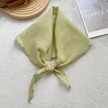 Detalle de pañuelo triangular de lino verde claro con bordes festoneados y tejido fino - Verde amarillento
