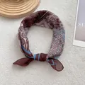 Close-up of vintage paisley print silk scarf showing smooth texture and detailed patterns - Coffee