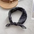 Detailed shot of black paisley silk scarf with checkered pattern knotted on textured fabric - Black Paisley Patchwork / Black