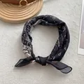 Dettaglio di sciarpa in seta con motivo paisley e trama satinata su sfondo elegante - Bandana / Nero