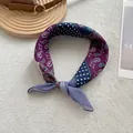 Detailed macro view of a paisley print silk scarf in purple and navy tones on white fur - Purple