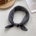 Vista dettagliata di un foulard in seta a pois bianchi e neri annodato con eleganza - Nero