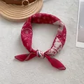 Dettaglio di un foulard di seta rosso con motivo paisley annodato su trama bianca - Bandana / Rosso