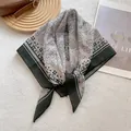 Detailed view of vintage paisley square scarf in grey and dark green tones on textures - Green