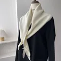Detailed macro view of the rib-knitted cream white shawl draped on a black blazer suit - Cream Rice