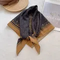 Close-up of silk-feel square scarf with paisley patterns on a vintage leather bag - Yellow