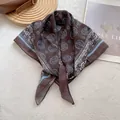 Detailed view of coffee paisley silk scarf tied elegantly on a soft white fur texture - Money Copper