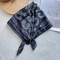 Close-up of black and white paisley silk square scarf on a minimalist lifestyle backdrop - Paisley Print / Black