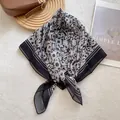 Détail d'un foulard en soie noir et blanc à fleurs posé sur un sac à main en cuir marron - 70x70cm / Moucheté Noir et Blanc