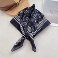 Detail of floral silk scarf with geometric border placed on a stylish leather bag - 70cmx70cm / Black