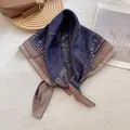 Detailed shot of dark blue and brown paisley printed silk scarf styled on a tote bag - Coffee