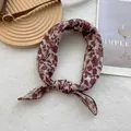 Détail d'un foulard en soie vintage avec motifs floraux rouges sur tissu crème noué - Fleurs Rétro Rouge Vin / Rouge