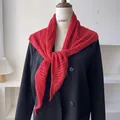 Detalle de chal de punto calado rojo que muestra textura ondulada sobre blazer negro - Rojo