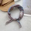 Primer plano de un pañuelo de seda bohemio con motivos florales vintage sobre fondo beige - Azul