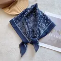 Close-up of navy blue paisley silk scarf tied in a knot on a minimalist textured background - Navy Blue