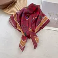 Detail of burgundy square scarf with bear prints and stripe edges on a magazine - Fruit Orchard Red