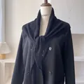 Detalle de un chal de punto calado negro anudado sobre un traje de doble botonadura fina - Negro